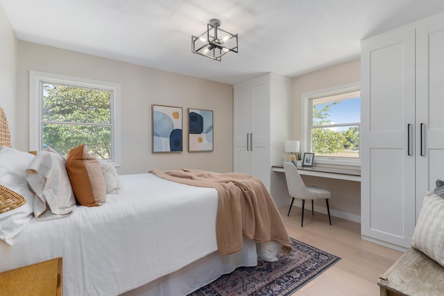 bedroom with light hardwood / wood-style flooring, multiple windows, and a notable chandelier