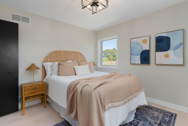 bedroom with light hardwood / wood-style floors and an inviting chandelier