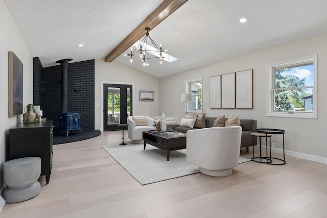 living room featuring a wood stove, a wealth of natural light, light hardwood / wood-style floors, and vaulted ceiling with beams