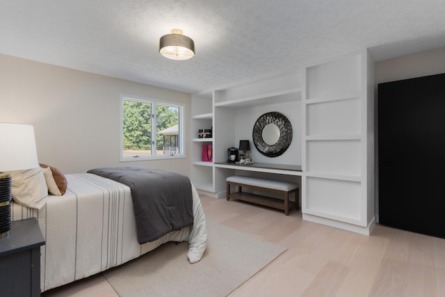 bedroom featuring light hardwood / wood-style flooring and a textured ceiling