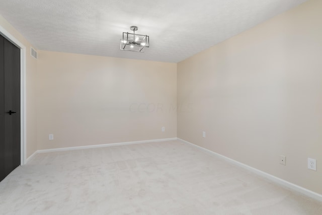 empty room with a textured ceiling and light carpet