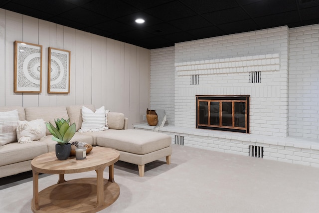 living room with a fireplace, light carpet, wooden walls, and brick wall