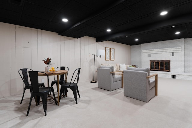 living room with a fireplace, light carpet, and wooden walls