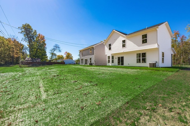 rear view of property with central AC and a lawn