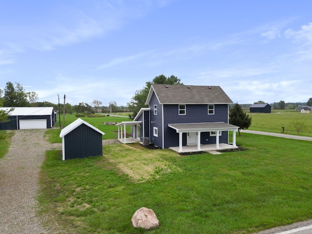 back of house featuring a porch, an outbuilding, and a yard