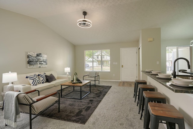 carpeted living room with a textured ceiling, a wealth of natural light, sink, and lofted ceiling