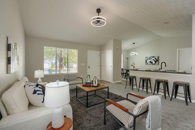 living room featuring a textured ceiling, sink, lofted ceiling, and carpet floors