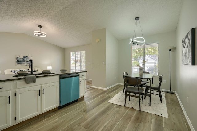 kitchen featuring white cabinets, decorative light fixtures, stainless steel dishwasher, and a healthy amount of sunlight