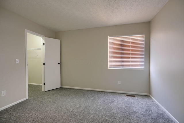 carpeted empty room with a textured ceiling