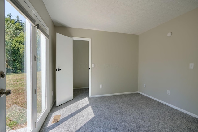 carpeted empty room featuring a textured ceiling