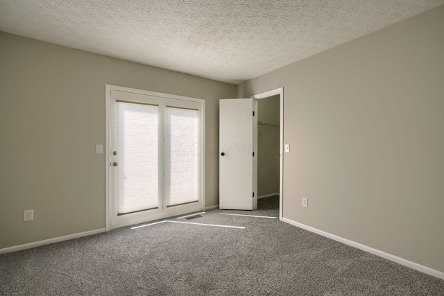 empty room with carpet and a textured ceiling