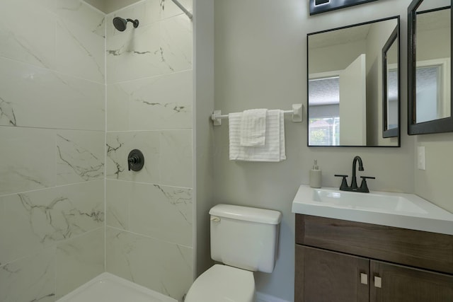 bathroom with toilet, vanity, and tiled shower