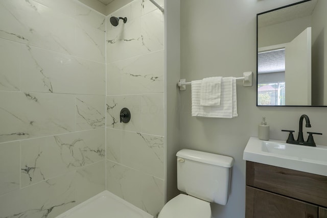 bathroom featuring vanity, toilet, and tiled shower