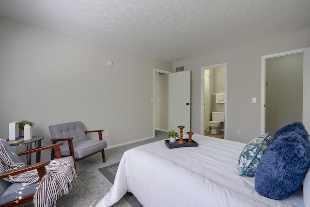 carpeted bedroom with ensuite bathroom and a textured ceiling