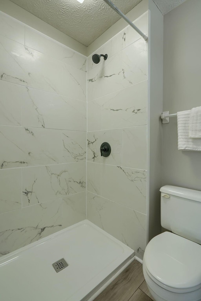 bathroom featuring tiled shower, a textured ceiling, and toilet