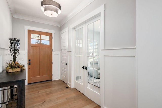 foyer entrance with ornamental molding, light hardwood / wood-style floors, and a healthy amount of sunlight