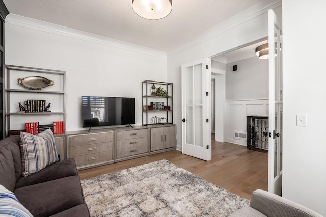 living room with crown molding, light hardwood / wood-style floors, and french doors