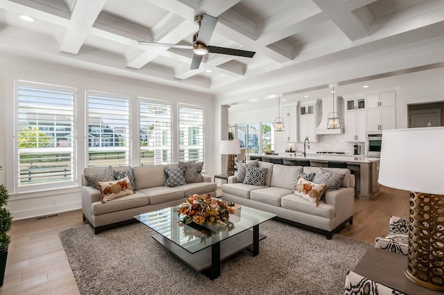 living room featuring coffered ceiling, beam ceiling, and light hardwood / wood-style flooring