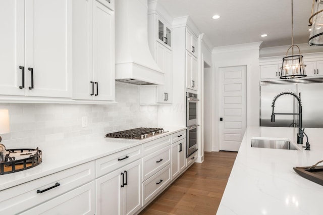 kitchen featuring appliances with stainless steel finishes, decorative light fixtures, sink, white cabinets, and custom exhaust hood