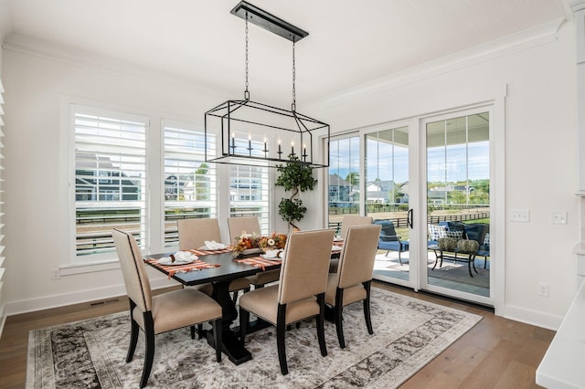 dining room featuring ornamental molding, hardwood / wood-style floors, and a notable chandelier