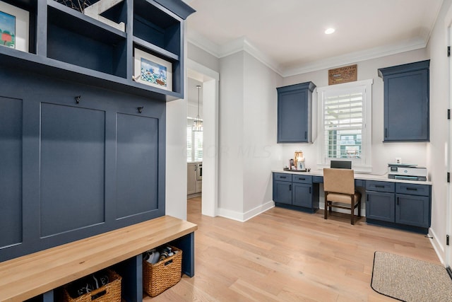 mudroom featuring crown molding, built in desk, and light hardwood / wood-style floors