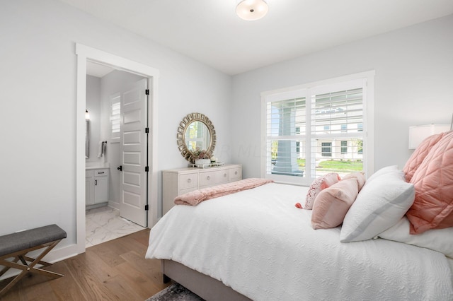 bedroom with ensuite bathroom and light hardwood / wood-style flooring