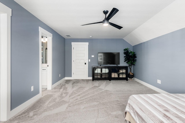 bedroom with ceiling fan, light colored carpet, ensuite bathroom, and vaulted ceiling