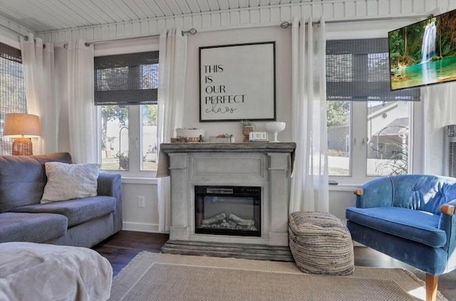 sitting room with plenty of natural light, dark wood-style flooring, and a glass covered fireplace