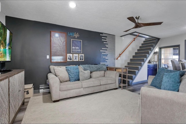 living room with a ceiling fan, stairway, a textured ceiling, and wood finished floors