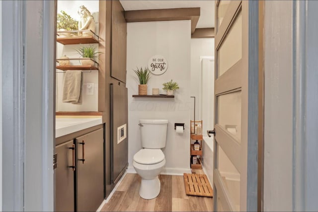 bathroom featuring toilet, wood finished floors, visible vents, vanity, and baseboards