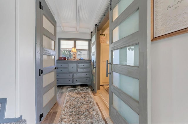 hall featuring light wood-type flooring and a barn door