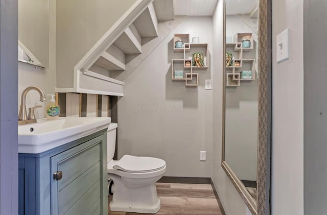 bathroom featuring toilet, baseboards, wood finished floors, and vanity