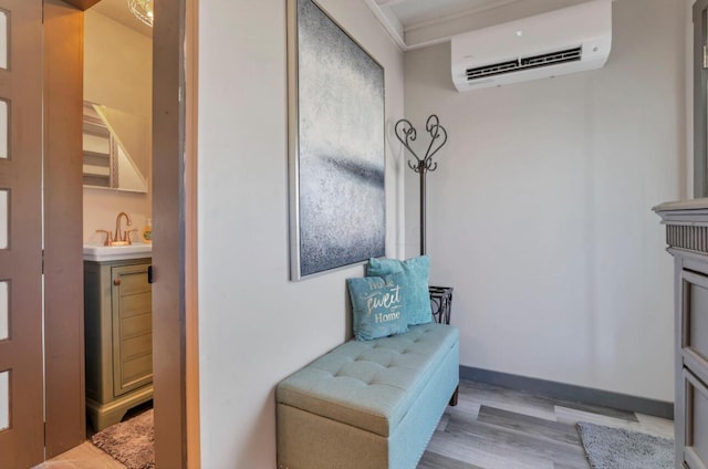 interior space featuring wood finished floors, a wall unit AC, a sink, and baseboards