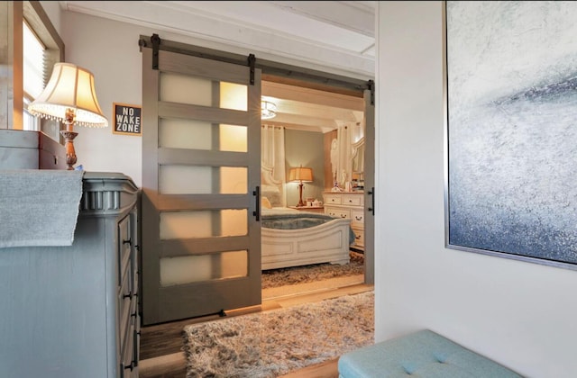 corridor with a barn door and wood finished floors