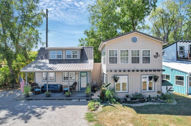 view of front of house featuring board and batten siding, a front yard, outdoor lounge area, and metal roof