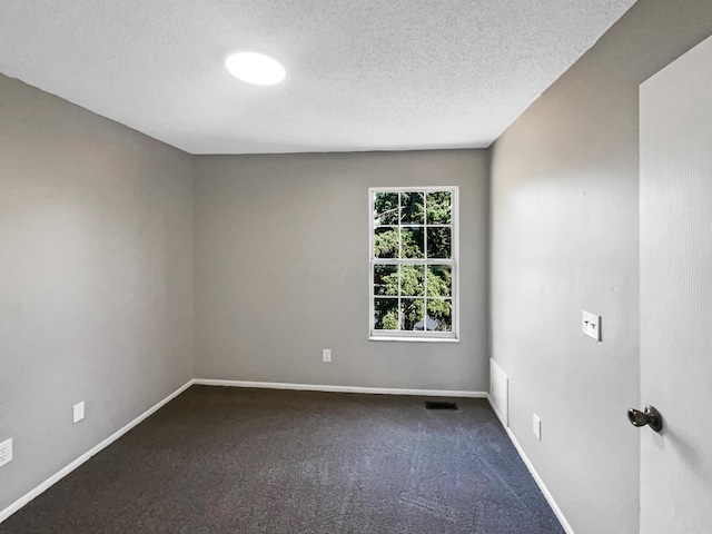 empty room featuring dark carpet and a textured ceiling