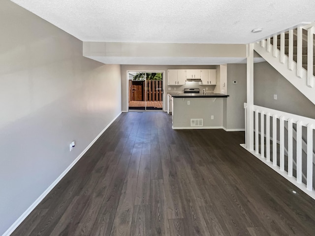 unfurnished living room featuring dark hardwood / wood-style flooring and a textured ceiling