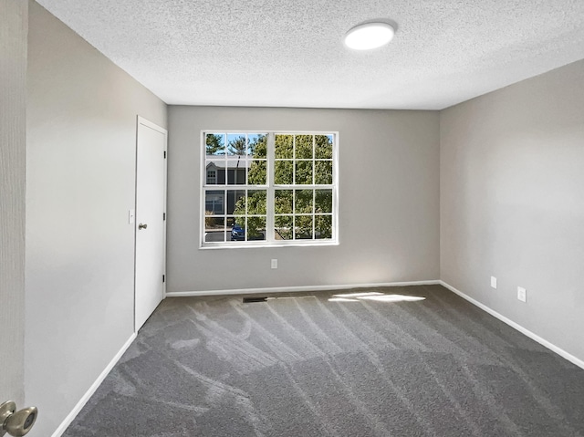 unfurnished room with a textured ceiling and dark carpet