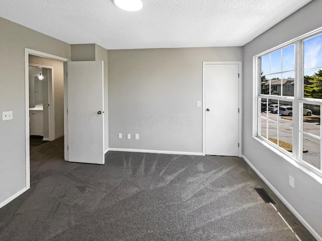 unfurnished room with dark carpet and a textured ceiling