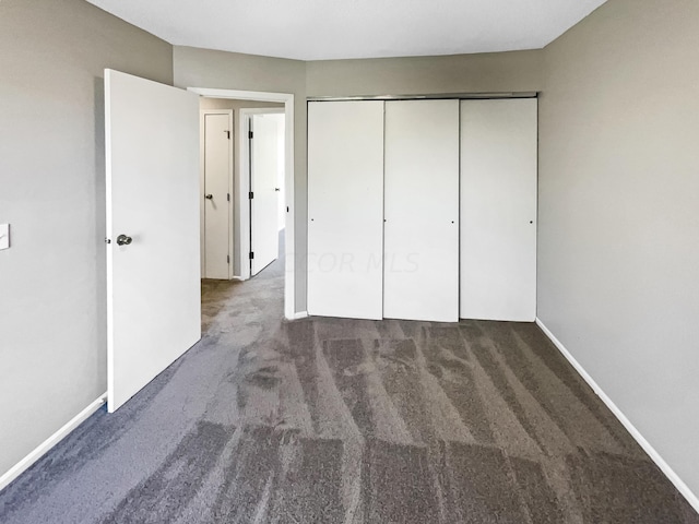 unfurnished bedroom featuring dark colored carpet and a closet