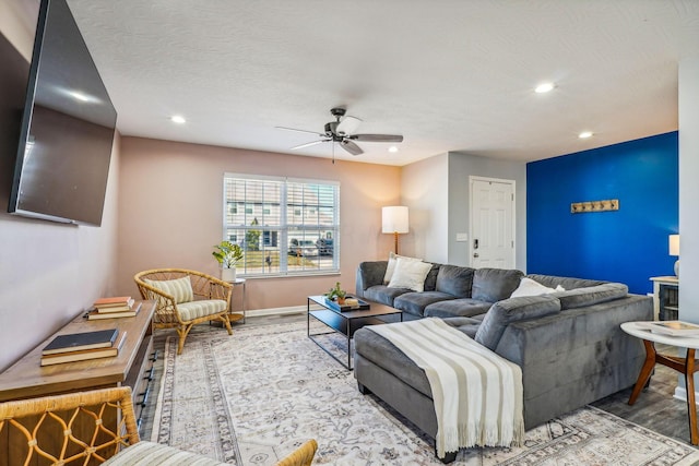 living room with ceiling fan, a textured ceiling, and hardwood / wood-style flooring