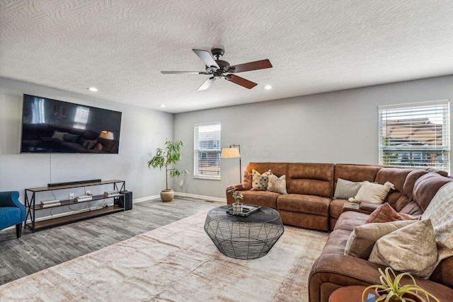 living room with a textured ceiling, light wood-type flooring, and ceiling fan