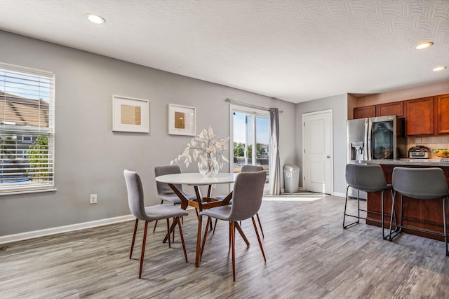 dining space with a textured ceiling, plenty of natural light, and dark wood-type flooring