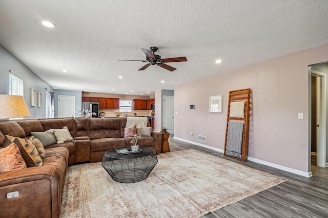 living room with ceiling fan, wood-type flooring, and a textured ceiling