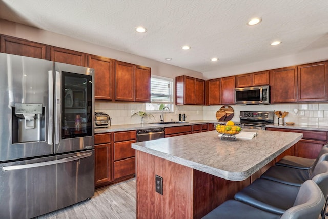 kitchen with a breakfast bar area, a kitchen island, a textured ceiling, and appliances with stainless steel finishes