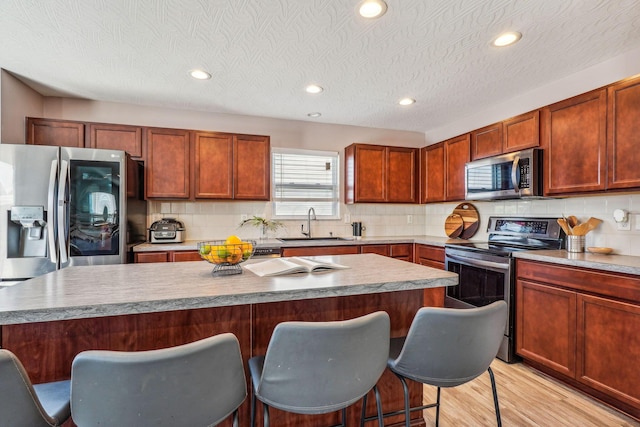 kitchen with a kitchen breakfast bar, sink, a kitchen island, and appliances with stainless steel finishes