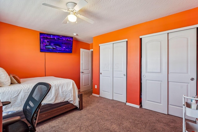 carpeted bedroom featuring a textured ceiling, ceiling fan, and two closets