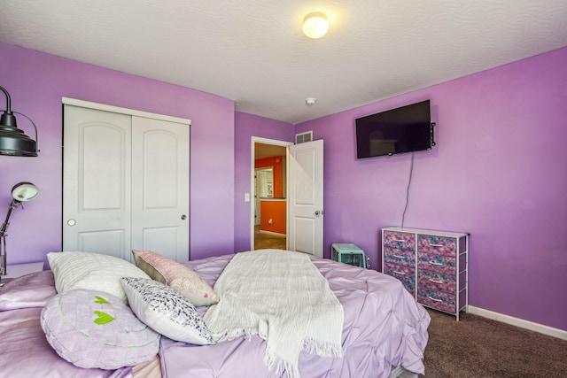 bedroom with a textured ceiling, carpet floors, and a closet