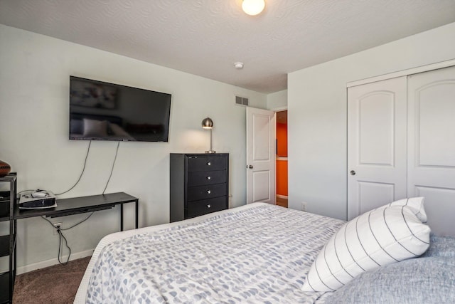 bedroom with a closet, a textured ceiling, and dark colored carpet