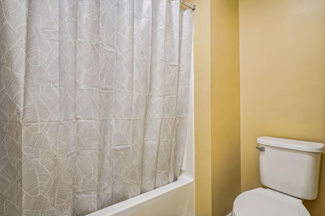 bathroom featuring shower / tub combo and toilet